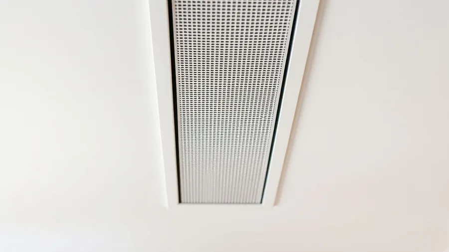 Grille de soufflage linéaire discrète intégrée dans un plafond blanc de séjour